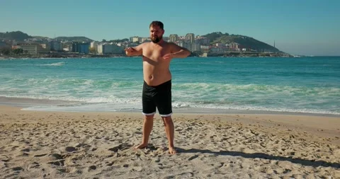 A man does morning exercises on the beach Stock Footage 171527419