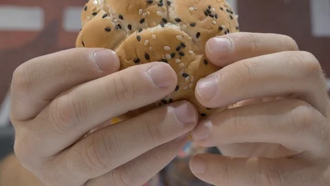 A man does not eat healthy food. He's eating a hamburger. Video stock 92411352