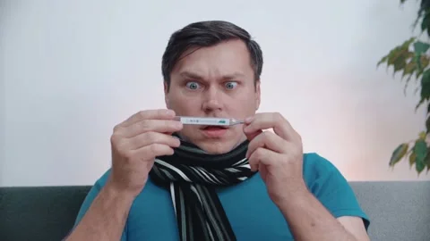 A man does not feel well looking at a thermometer. Close-up. 스톡 동영상 146707692
