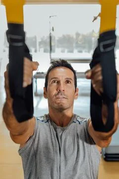 Man does a physical exercise with suspension training straps for workout. Stock Photos