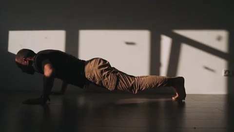A man does push ups from the floor in a room A soldier trains at home A shadow Stock Footage 154304215