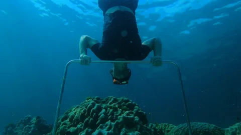 A man does push-ups on a horizontal bar dug into the seabed Stock Footage 275325990