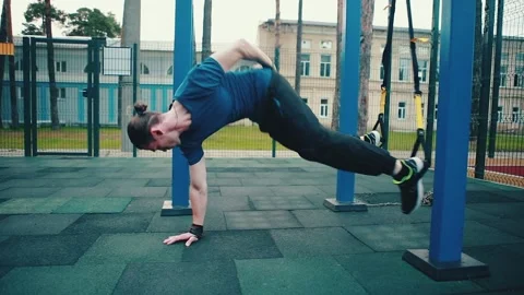 A man does push-ups on one hand, an athlete trains on an outdoor sports Stock Footage 149750383