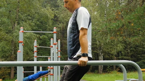 A man does push-ups on parallel bars Stock Footage 66549189