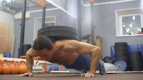 Man does push-ups with weight on his back Stock Footage 122695757