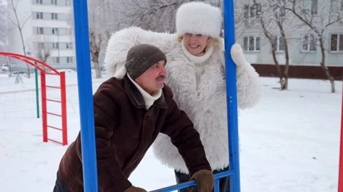 Man does push-ups while woman cheers on winter playground 스톡 동영상 330106326