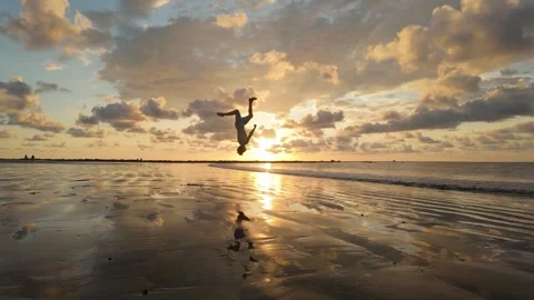 Man does Roundoff Backflip in front of stunning Sunset Stock Footage 302939289