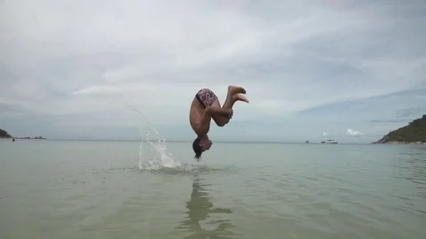 Man does Slow Motion Backflip in Shallow Ocean Water Stock Footage 79161235