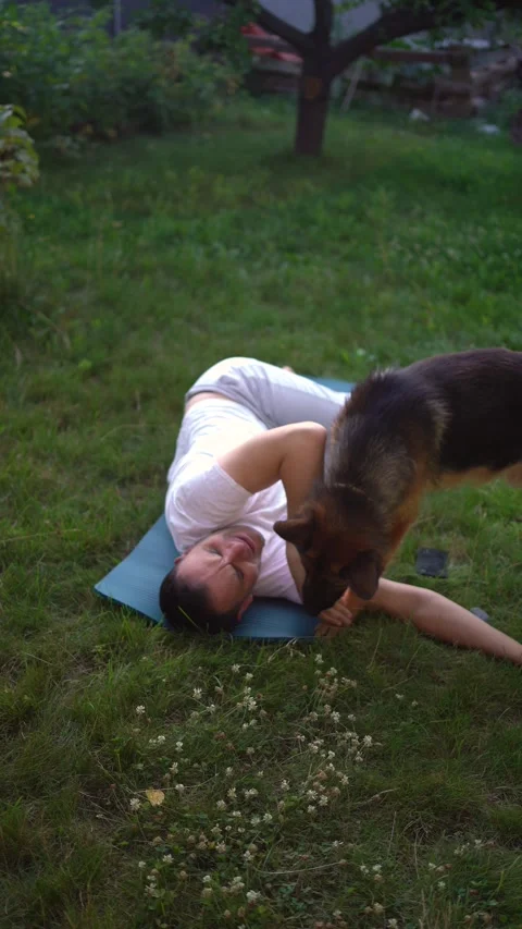 A man does somatic exercises with his dog in the garden in the morning Stock Footage 279248770