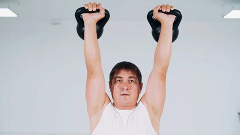 A man does a squat with a kettlebell. A man in the studio lifts weights and does Video stock 114051593