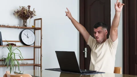 Man does a victory dance at his laptop at home. Stock Footage 310526703