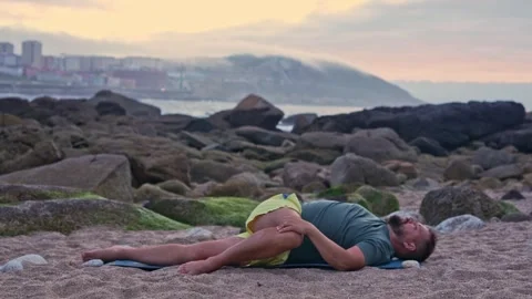 A man does a warm-up, lies on the ocean on the sand, does a stretch. Stock Footage 242347291