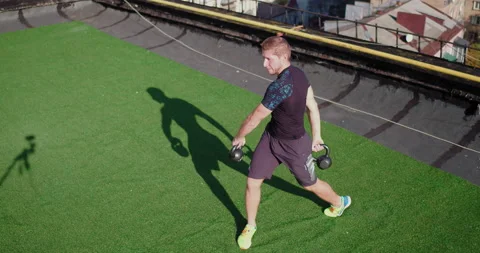 Man does workout with weights. Caucasian athlete trains with weighters on roof Video stock 143153911