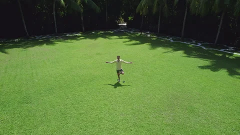 Man does yoga on the lawn against the background of palm trees Stock Footage 243296544