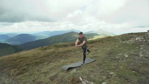 A man does yoga in the mountains, plays the swallow exercise. Yoga at the top Stock Footage 214322858