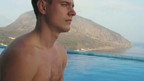 Man does yoga by the pool, with sea and mountain views Stock Footage 131461735