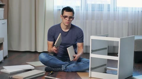 A man doesn't know how to assemble furniture Stock Footage 146460636