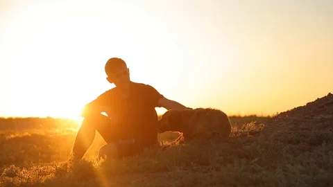 Man with a dog in the meadow at sunset Video stock 89930273