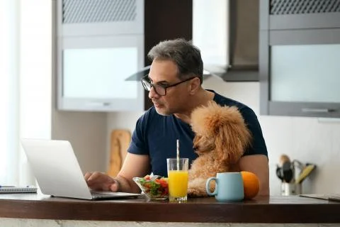 Man with the dog working using a laptop at home. Foto stock