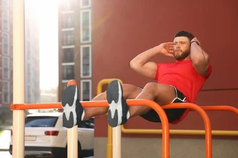 Man doing abs exercise on parallel bars at outdoor gym Stock Photos