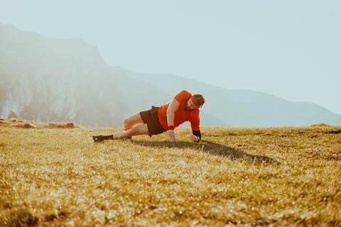 A man doing abs exercises on top of a mountain Foto stock