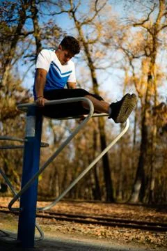 Man doing abs workout on parallel bars outdoors on fall during sunset Stock-Fotos