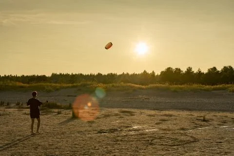 Man doing activities on the beach with abstract sun flare and sunset Stock Photos