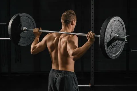 Man doing back squats exercise with a barbell. Stock Photos