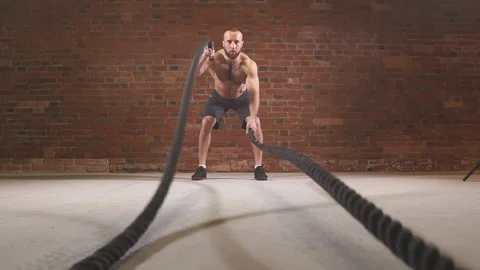 Man is doing battle rope exercise while working out at cross-fit training. Slow Stock Footage 102157657
