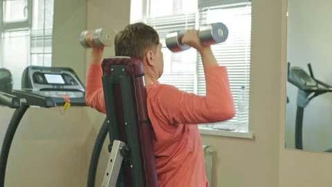 A man doing a bench press with dumbbells sitting with a straight grip in a Stock Footage 107404041