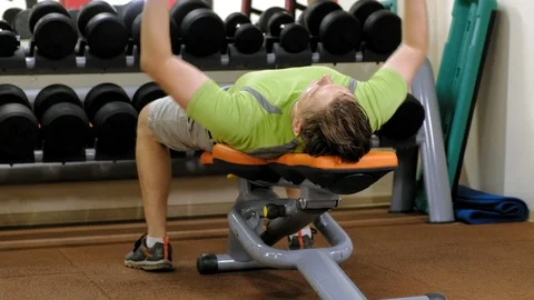 Man doing bench press with dumbbells in fitness studio Stock Footage 111508227