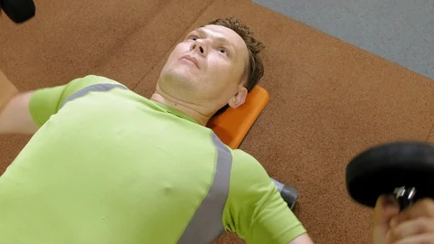 Man doing bench press with dumbbells in fitness studio Stock Footage 111509749