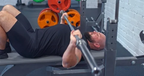 Man doing a bench press lying on a bench in the gym. Warming up muscles lying on 스톡 동영상 124372496