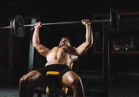 Man doing bench presses with weights in a bar indoors Stock Photos