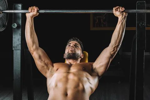 Man doing bench presses with weights in a gym Stock Photos