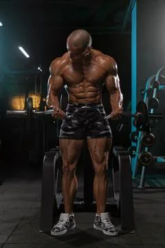 Man doing biceps exercise while standing with barbell. Stock Photos