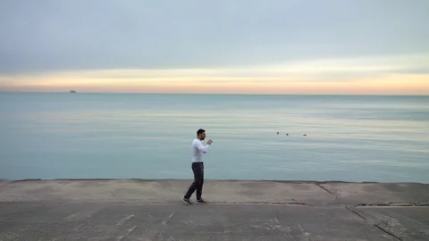 Man is doing boxing exercises on the ebankment. Athlete training outdoors. Sea Stock-Footage 82658250