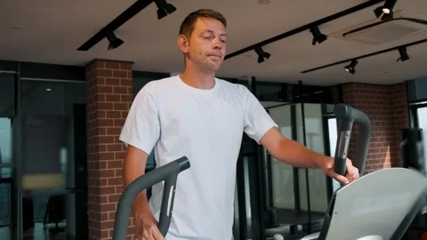 Man doing cardio training on elliptical machine in modern fitness studio in Video stock 282923470