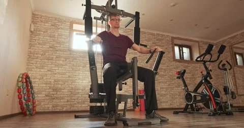Man doing chest press exercise on multifunctional home gym machine, pushing Stock-Footage 313555356