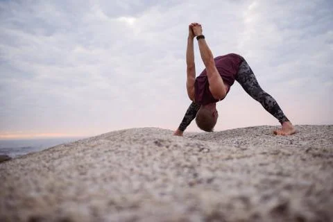 Man doing the clasp hands forward fold pose outdoors Stock-Fotos