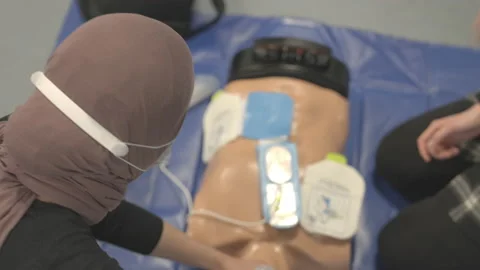 Man Doing Compressions While Being Assisted By Woman Turning Defibrillator Stock Footage 154952198