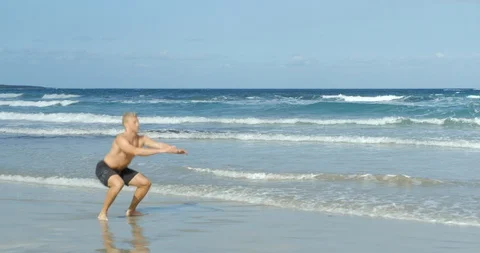 A Man doing Crossfit Squat Jumps on a Sunny Beach Vídeo Stock 85512056