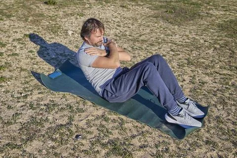Man doing crunch exercise on mat outdoor abdominal workout training Stock Photos