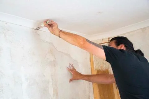 Man  doing  DIY on interior  walls  filling  cracks  in plaster  and   stone Stock Photos