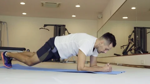 Man doing dynamic plank in gym. Position plank on floor with elbows and toes Stock Footage 92527748