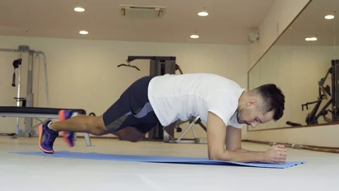 Man doing dynamic plank in gym. Position plank on floor with elbows and toes Video stock 92527908