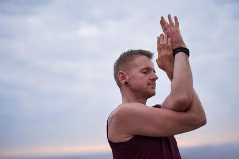 Man doing the eagle pose by the oceanat dusk Stock-Fotos