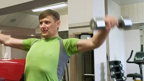 A man doing an exercise on the back delta with dumbbells sitting with a straight Stock Footage 108071924