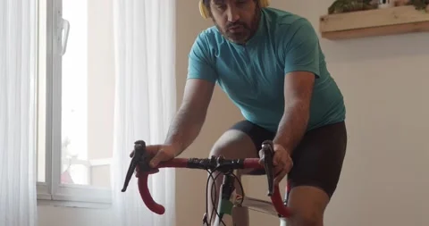 Man doing exercise bike at home while listening to music. Stock Footage 145908104