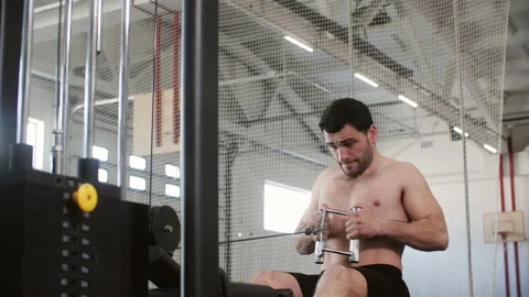 Man is doing exercise for chest muscles on cable row crossover machine in gym. Видео 234549721